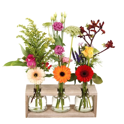 3 flessen met bloemen in een houder